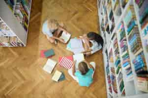 Foto gratuita vista dall'alto dei bambini che studiano sul pavimento in biblioteca