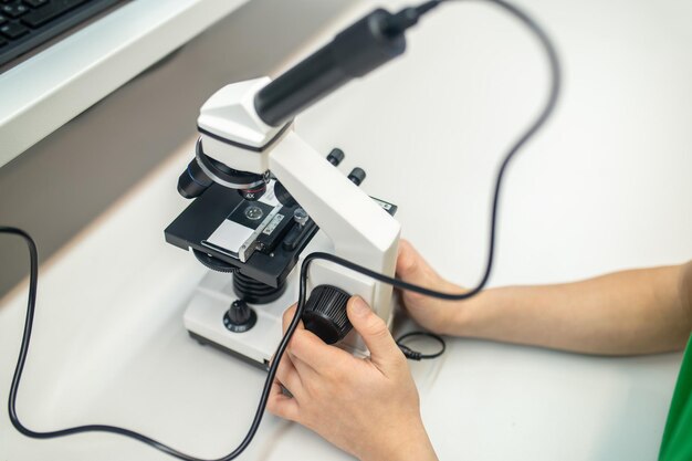 Вид сверху на детские руки, трогающие микроскоп