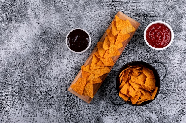 Top view chips in black pan and sauses in bowls and copy space on left on white stone