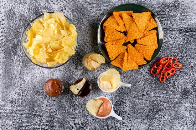 Top view chips in bowl with sauses and pepper on white stone  horizontal