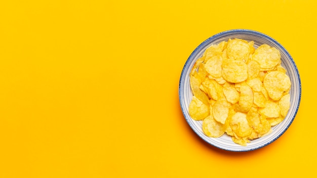 Top view chips bowl on yellow background