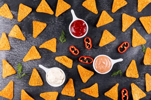 Top view chips pattern with pepper dill and sauses in bowls on black stone  horizontal