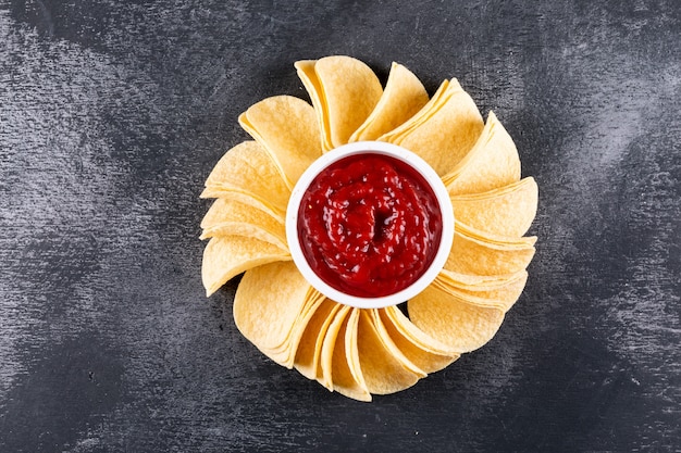 Top view chips with sause in bowl on black stone  horizontal