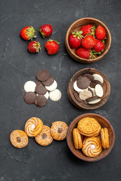 Top view choco cookies with strawberries and biscuits on dark desk