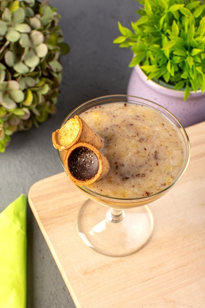 Free photo a top view choco dessert brown with ice cream inside transparent glass along with flowers on the grey