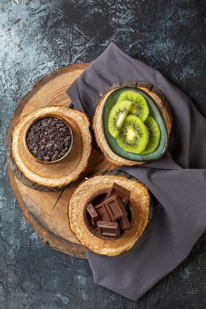 Top view chocolate bars with fresh sliced kiwis on dark-grey surface cake color breakfast sugar fruit dessert