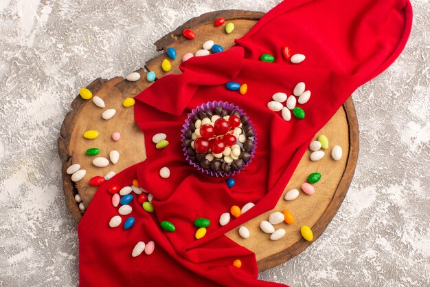 Top view chocolate brownies with cranberries and candies on the light background cake biscuit bake