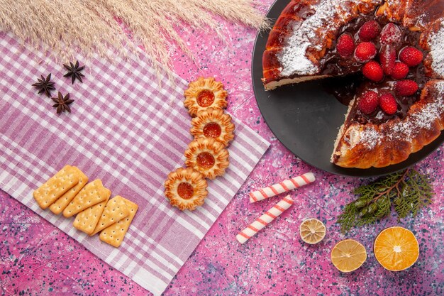 Top view chocolate cake with strawberries crackers and cookies on the pink desk sugar sweet biscuit cookie