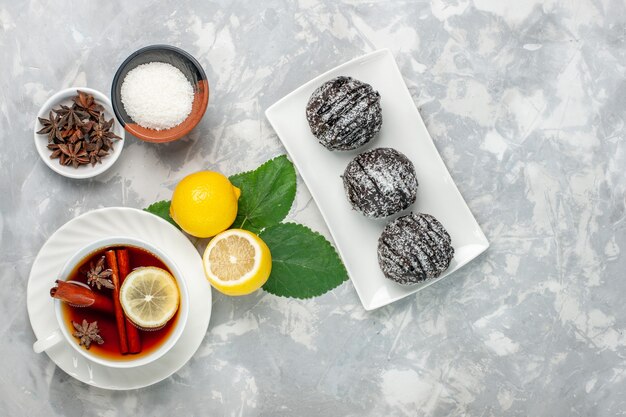 Top view chocolate cakes with lemon and cup of tea on the white surface