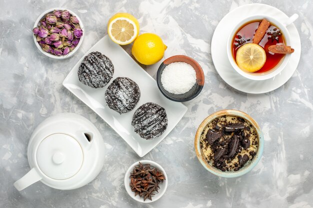 Top view chocolate cakes with lemon and tea on white surface