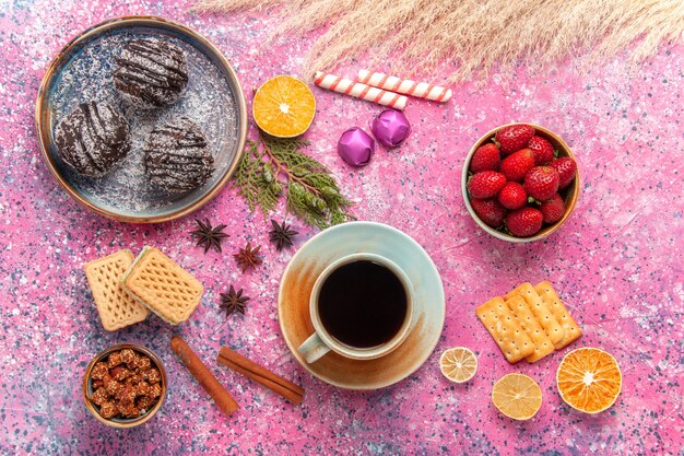 Top view chocolate cakes with waffles and cup of tea on pink