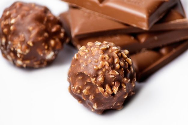 Top view of chocolate candy balls with chocolate bars on a white surface