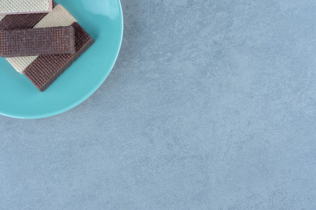 Top view of chocolate and caramel waffles on blue plate.