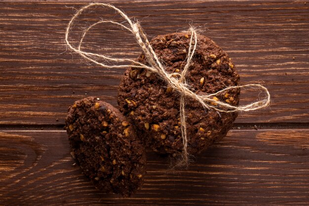 Foto gratuita vista superiore dei biscotti di pepita di cioccolato con i dadi e il cacao di cereali legati con una corda su di legno