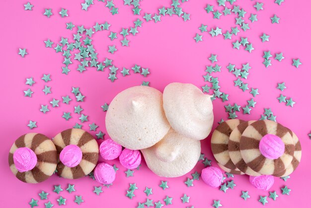トップビューチョコレートクッキーとピンクの机の上のメレンゲ、クッキーキャンディシュガーカラー