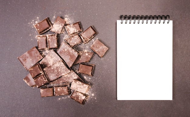 Top view chocolate covered in cocoa with notebook 