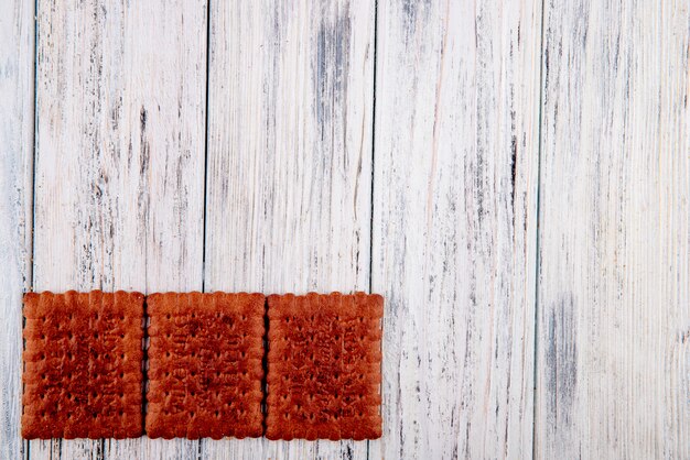 top view Chocolate crackers on the left with copy space on white wooden background