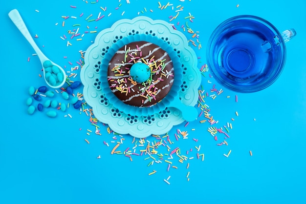 青い机の上にカラフルな小さなキャンディー、ケーキビスケットシュガー甘いおいしいチョコレートドーナツのトップビュー