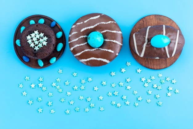 A top view chocolate donuts with blue candies on blue desk, candy sweet sugar color