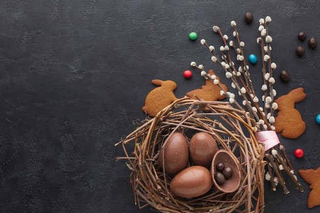 Top view of chocolate easter eggs in nest with candy and copy space