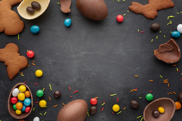 Top view of chocolate easter eggs with candy and cookies frame