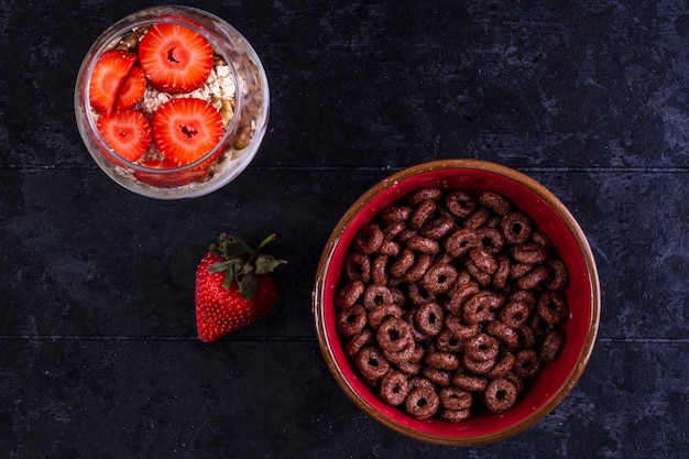 top view chocolate flakes in a bowl with muesli in a glass with fruit and strawberries