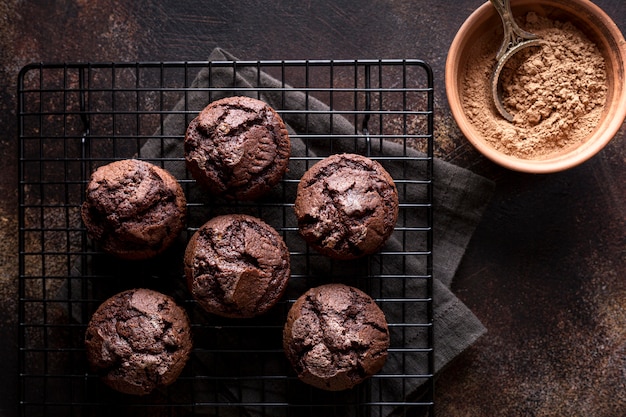 Vista dall'alto di muffin al cioccolato su rack di raffreddamento con cacao in polvere