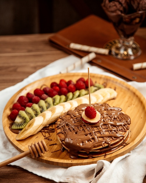 Free photo top view chocolate pancakes with banana kiwi and strawberries on a tray