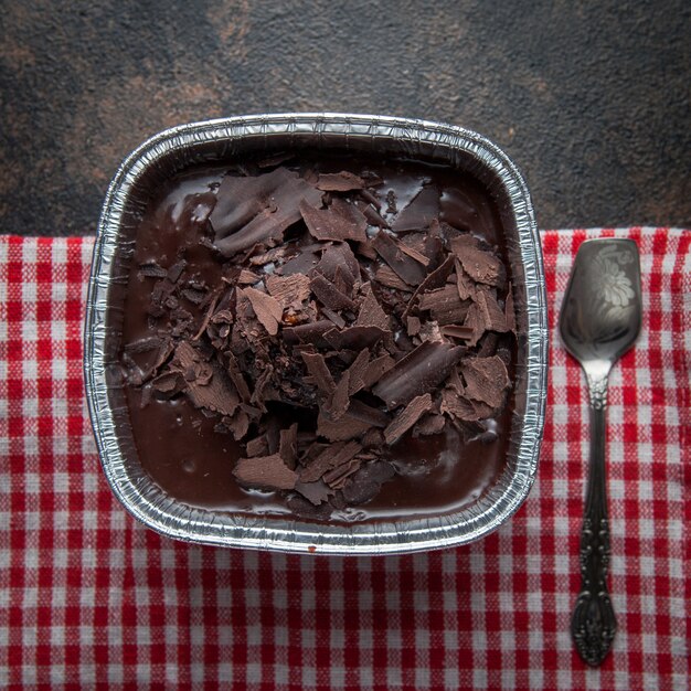 Foto gratuita budino al cioccolato vista dall'alto con cucchiaio e straccio antichi nel piatto di alluminio