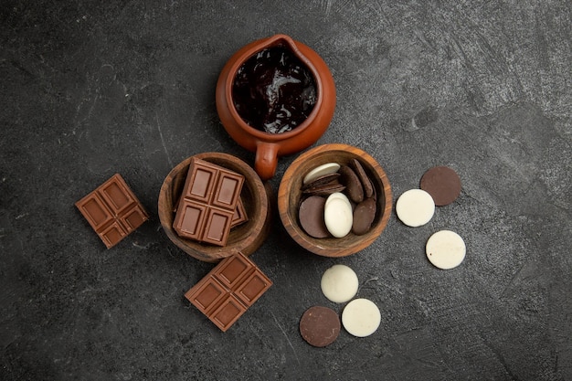 Вид сверху шоколад на столе на темной поверхности шоколад и шоколадный соус в мисках