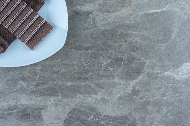 Top view of chocolate wafers on white plate. On the grey table.