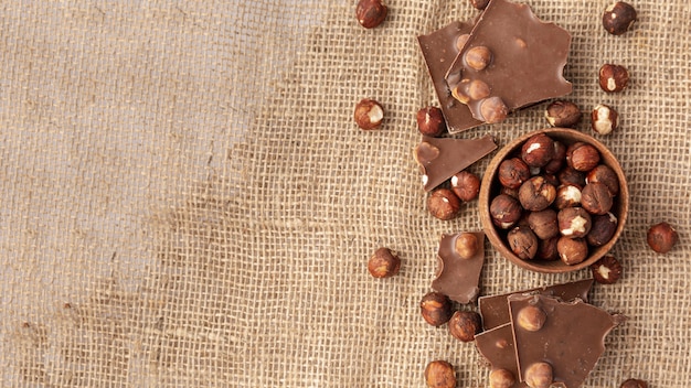 Top view of chocolate with hazelnuts on burlap and copy space