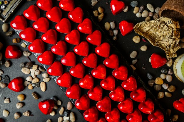 Top view chocolates in the shape of a red heart on a stand with pebbles