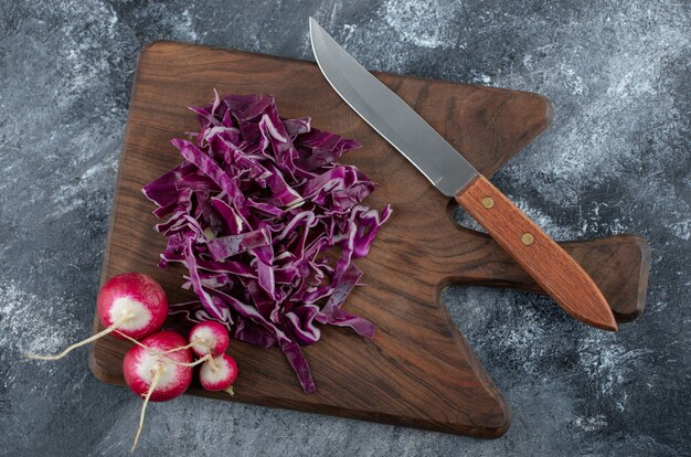 Top view of Chopped cabbage and radish on wooden board over grey background. 