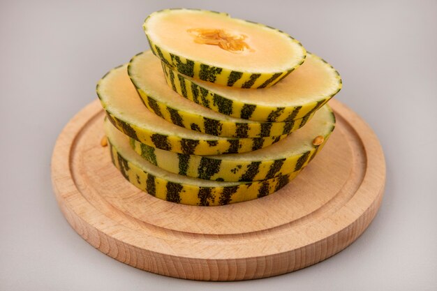 Top view of chopped slices of cantaloupe melon on a wooden kitchen board on a grey wall