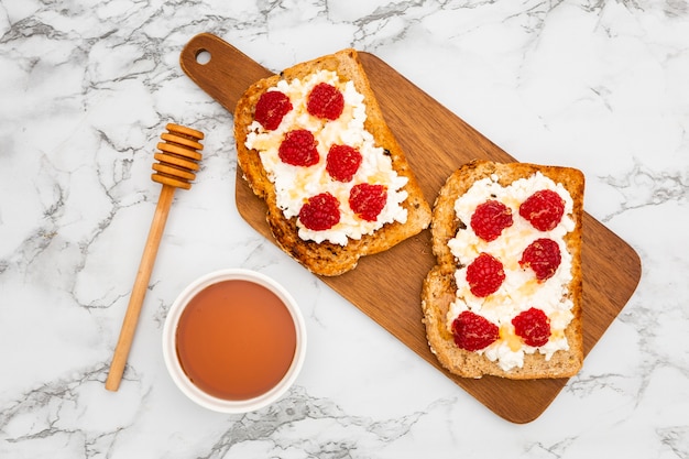 Free photo top view of chopping board with toast and raspberries