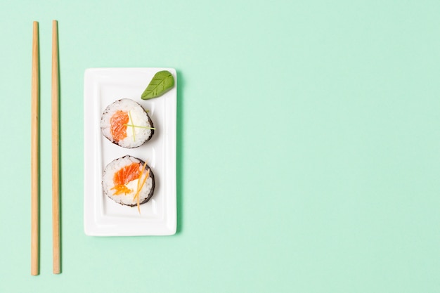 Top view chopsticks beside plate with sushi