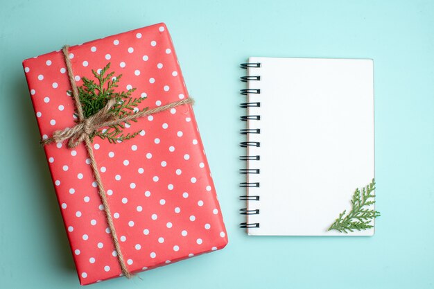 Top view of Christmas background with gift box and spiral notebook on pastel green background