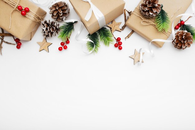 Top view of Christmas composition with gift box, ribbon, fir branches, cones, anise on white table