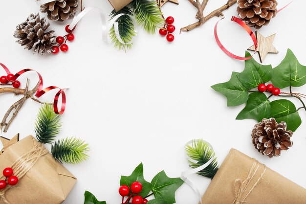 Top view of Christmas composition with gift box, ribbon, fir branches, cones, anise on white table