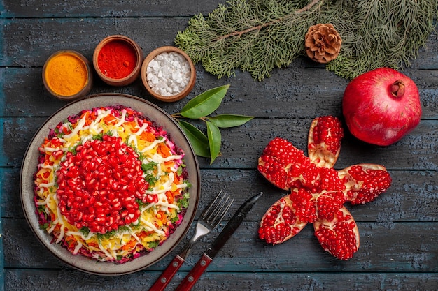 上面図クリスマス料理ザクロのニンジンジャガイモとさまざまなスパイスのピルドザクロボウルの横にあるクリスマス料理テーブルの上の円錐形のトウヒの枝