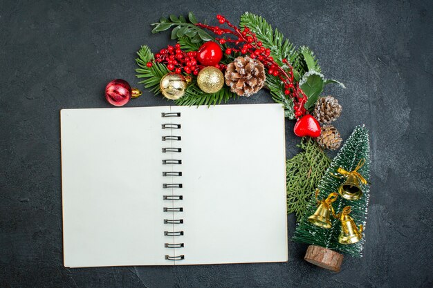 Top view of christmas mood with fir branches xsmas tree next to spiral notebook on dark background