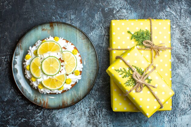 Free photo top view of christmas yellow gift boxes and cake decorated with lemon limes on dark background