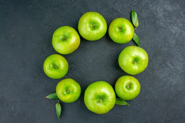 Top view circle row green apples on dark table