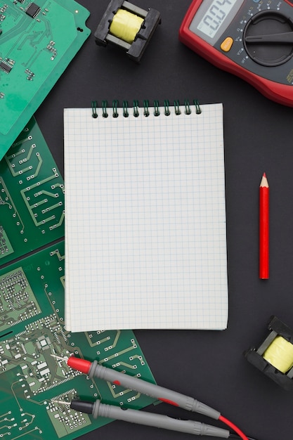 Free photo top view circuit board with a blank notepad