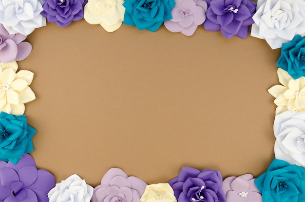 Free photo top view circular frame with paper flowers and brown background