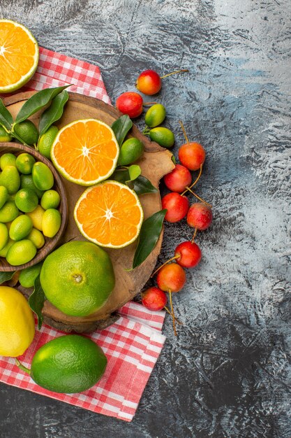 Top view citrus fruits apples citrus fruits on the board on the checkered tablecloth cherries