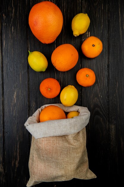 木製の背景に袋からこぼれるグレープフルーツレモンタンジェリンとして柑橘系の果物のトップビュー