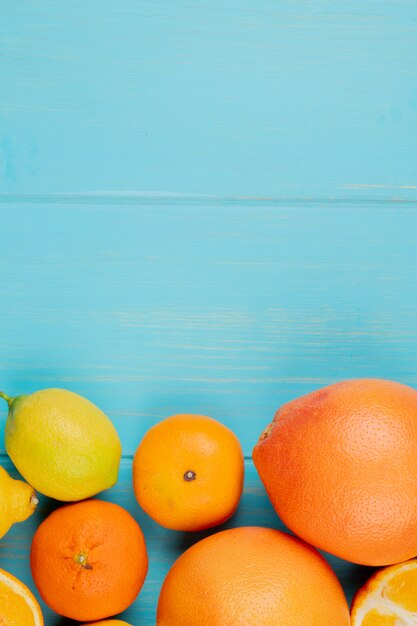 Top view of citrus fruits as orange lemon and tangerine on blue background with copy space