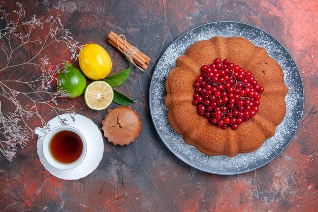 Top view citrus fruits a cake with berries cinnamon a cup of tea lemon cupcake tree branches